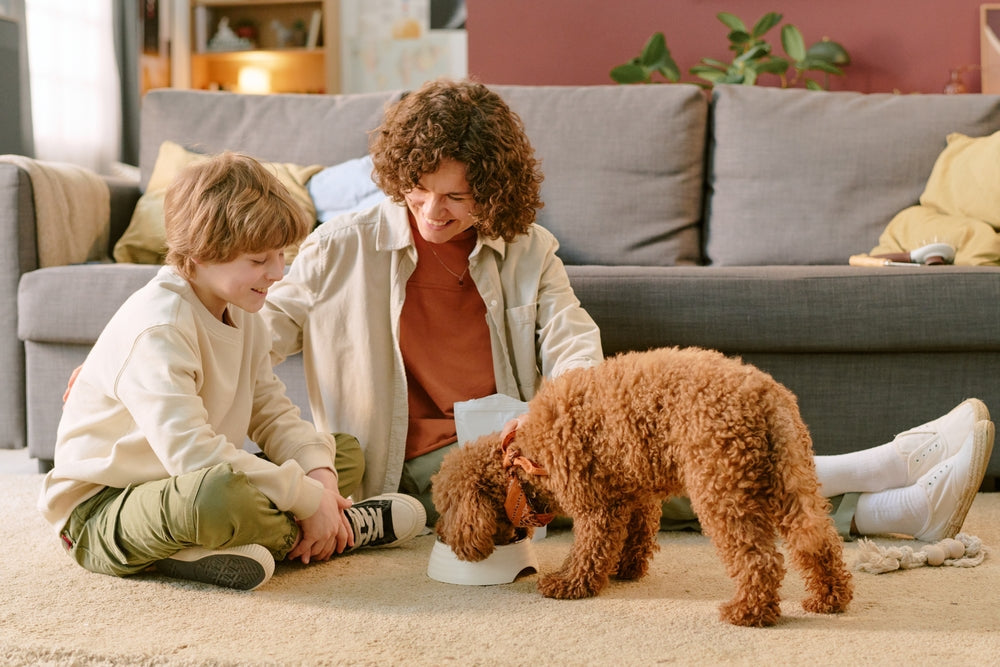 Mother and son smiling, feeding their dog a bowl of food